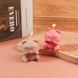 Candele profumate a forma di orsetto rosa e grigio esposte su un vassoio di legno