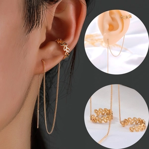 Dettaglio di ear cuff dorato e orecchino a catena lunga con trama in metallo traforato