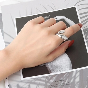Detail of adjustable silver open ring with abstract leaf design on woman's finger