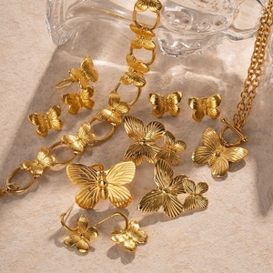 Golden butterfly jewelry set featuring necklaces, bracelets and earrings on stone background