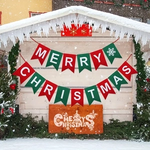 Festive red and green Merry Christmas felt banner with snowflakes on a snowy cabin