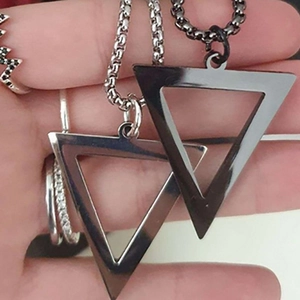 Close-up of silver and black triangular titanium steel pendants held in hand