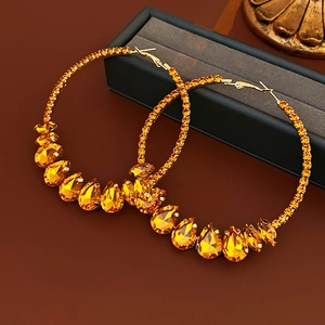 Macro view of gold hoop earrings with amber water-drop gems and sparkling crystals