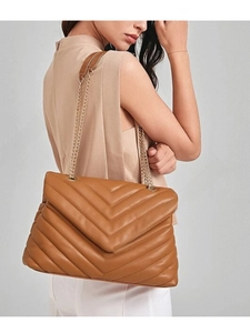 Detail of tan quilted leather shoulder bag with chevron stitching and gold chain strap