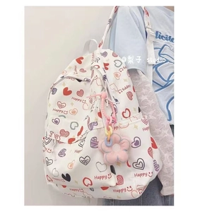 Detail of white backpack with heart and Happy prints featuring a pink flower plush charm