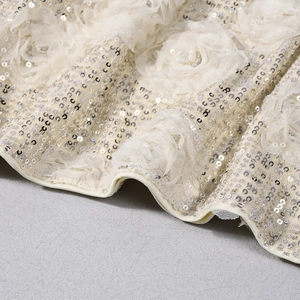 Macro detail of off-white mesh fabric with 3D lace flowers and silver sequins decoration