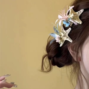 Detail showing two gold starfish hair claws with colorful flowers on brown hair