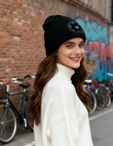 Street style black knit beanie featuring a dark floral patch against a graffiti wall