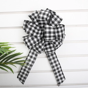Large black and white buffalo plaid Christmas bow decoration on a white wood background