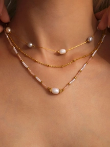 Dettaglio della collana a tre strati in oro con perle bianche e perline rosa tenui