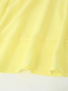 Detailed close-up of the hem stitching and soft yellow chiffon fabric drape on the dress