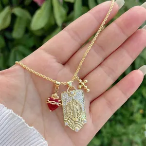 Détail du collier plaqué or 18 carats avec cœur rouge, médaillon gravé et pendentifs croix