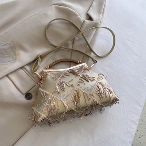 Detail of golden tassel evening bag with shiny sequins and curved metal handle