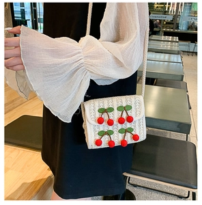 Straw square bag with cherry charms worn by a model in a casual setting