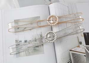 Close-up of clear PVC belts featuring pearl round buckles in gold and silver finishes