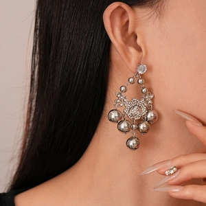 Boucles d'oreilles argentées avec fleurs en zircon et pompons boules sur un mannequin