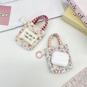 Floral mini pouch with metal ring and snap button for earphones shown in a flat lay setup