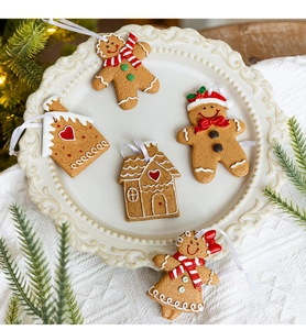 Five assorted Christmas gingerbread house and person ornaments in a white ceramic dish