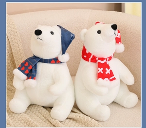 Close-up of white plush polar bears wearing blue and red festive scarves and hats