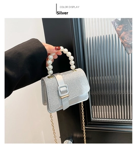 Close-up of silver glitter crossbody bag with elegant pearl handle and gold chain