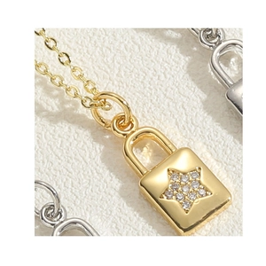 Macro shot of 14K gold plated lock pendant with zircon star inlay on a fine chain