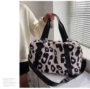 Close-up of cow print travel bag with durable straps and gold hardware detail