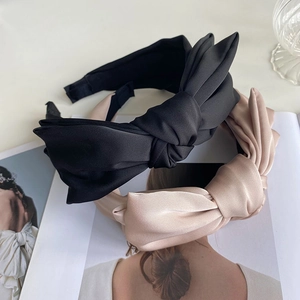 Detail of satin bow headbands in black and beige displayed on a fashion magazine