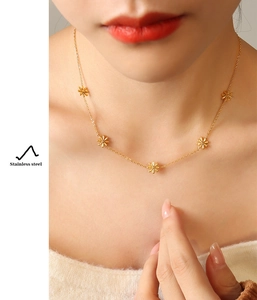 Close-up of golden stainless steel necklace featuring delicate daisy flower pendants