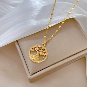 Elegant gold tree of life necklace with pavé crystals on a beige jewelry box backdrop