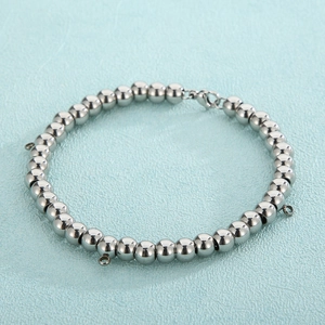 Detailed macro view of polished stainless steel ball bracelet with lobster clasp and charms