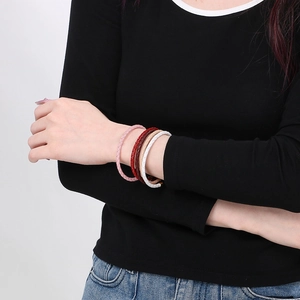 Set di quattro bracciali in pelle intrecciata rosa, bordeaux, crema e bianco indossati al polso