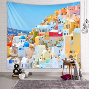 Santorini landscape tapestry hanging on a white brick wall in a cozy room setting