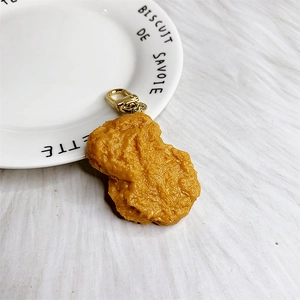 Macro detail of realistic golden fried chicken nugget keychain with gold metal lobster clasp
