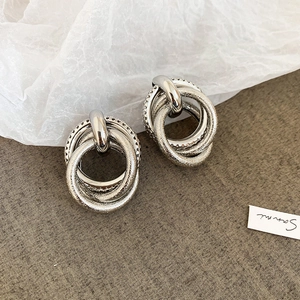 Detailed view of silver layered metal stud earrings with twisted geometric knotted design