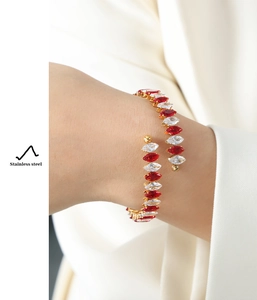 Detail of gold stainless steel wrap bracelet featuring red and white marquise zircons