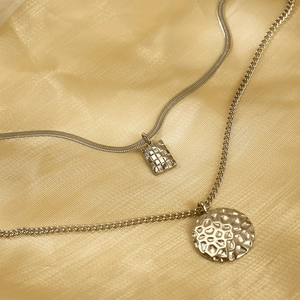 Detail of silver double-layer necklace with hammered rectangular and round pendants