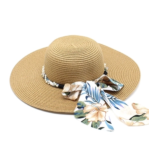 Detailed view of wide brim straw hat with floral ribbon bow and pearl string decoration