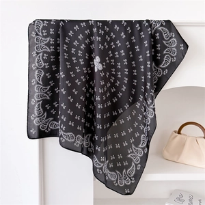 Detail of a black paisley silk scarf elegantly draped on a mantelpiece background