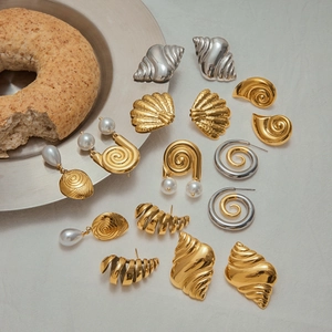 Detailed flat lay of gold and silver pearl earrings with seashell and spiral motifs