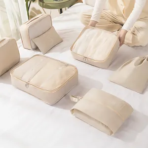 Beiges Reise-Organizer-Set mit Netztaschen und Kordelzugbeuteln auf weißem Bett