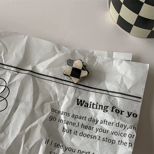 Star-shaped hair claw clip with black and cream checkerboard pattern on aesthetic paper