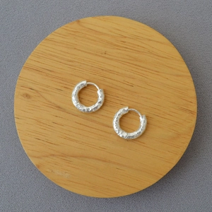 Silver hammered texture hoop earrings on a minimalist wooden tray display