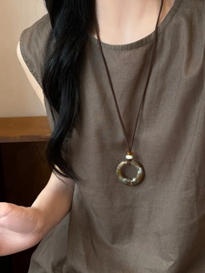 Detail of vintage resin pendant necklace with marble texture on linen clothing