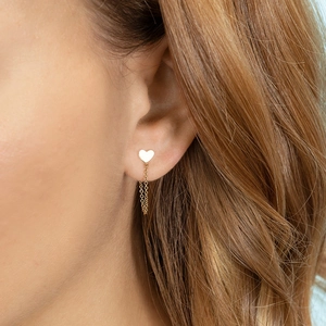 Elegant gold heart stud earrings with long tassel chains worn by a model in natural light