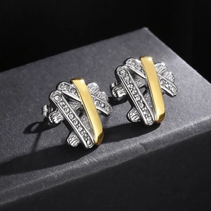 Macro detail of X-shaped hip hop stud earrings with silver and gold plating and white crystals