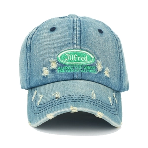 Detail einer blauen Denim-Basecap mit grüner Alfred-Stickerei und modischen Destroyed-Effekten