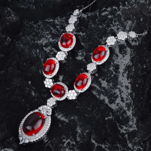 Detailed view of silver necklace with oval pigeon blood red rubies and a pear-shaped pendant