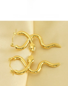 Detail of 18k gold plated snake-shaped earrings on elegant silk background