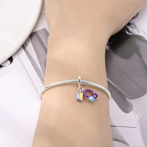 Detailed close-up of a silver snake chain bracelet with purple headset and tape charms