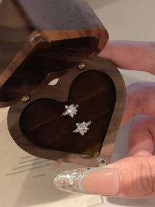 Close-up of zircon star rings in a wooden heart box held by hand for a romantic gift